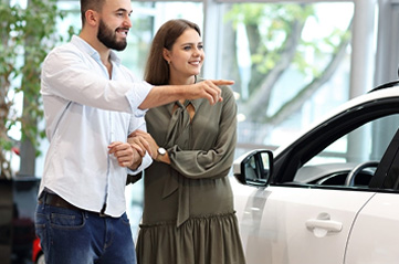 Couple looking at a white car in a showroom 