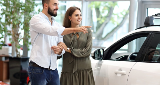 Couple looking at a white car in a showroom 