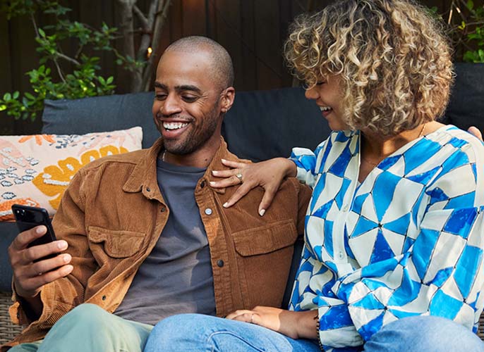 A man sitting and looking at his cellphone with a woman