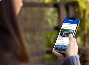 A woman browses cars on her smartphone