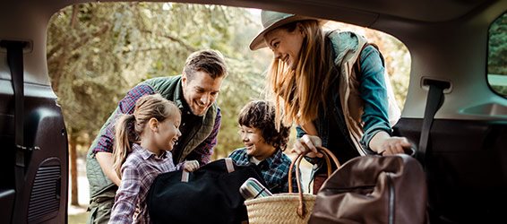 Man and woman with two children packing a car