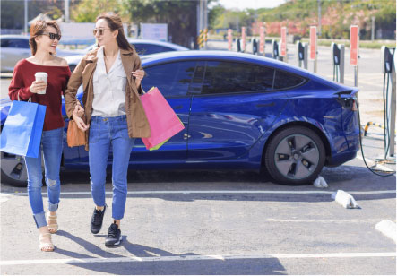 Two women walk away from their Subaru electric vehicle as it charges in a parking lot