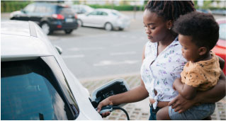 A mother holds her child as she charges her Subaru electric vehicle