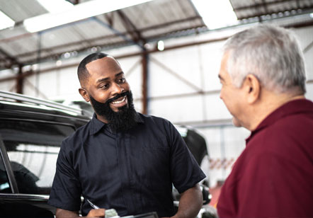 A mechanic in a garage speaks to a man about his Subaru electric vehicle