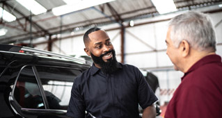 A mechanic in a garage speaks to a man about his Subaru electric vehicle