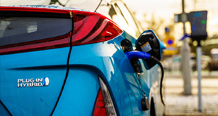 A 2023 Subaru Crosstrek Hybrid charging on the street