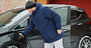 A man dressed for cold weather attaches a charger to his Subaru electric vehicle