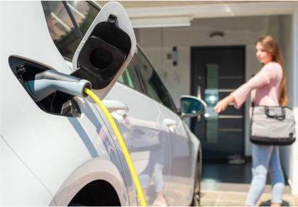 An electric vehicle charging in a woman's garage