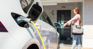 An electric vehicle charging in a woman's garage