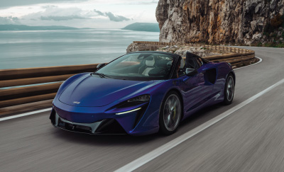 A McLaren Artura electric vehicle speeding down the road above the ocean